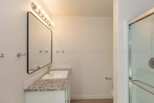 a bathroom with a granite countertop sink a mirror and shower