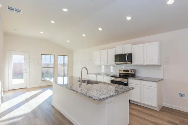 a kitchen with granite countertop a sink stove and cabinets