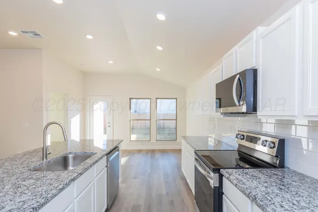 a kitchen with granite countertop a stove and a sink