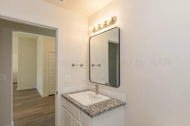 a bathroom with a granite countertop sink and a mirror