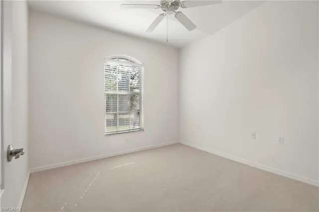 an empty room with a window and a fan
