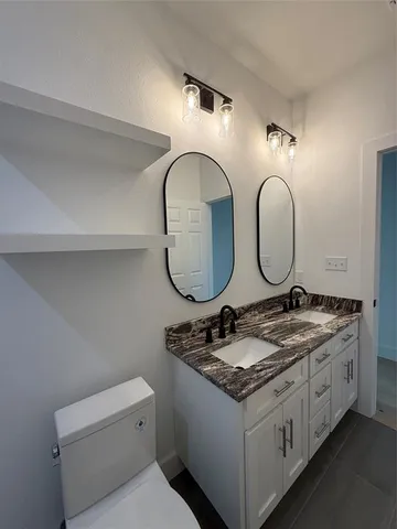 a en suite bathroom with a granite countertop toilet a sink and a mirror