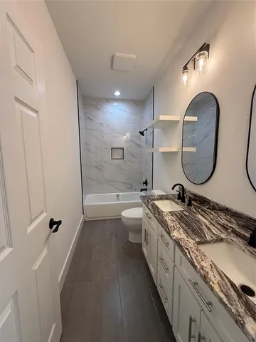 a spacious bathroom with a granite countertop double vanity sink a mirror and a shower
