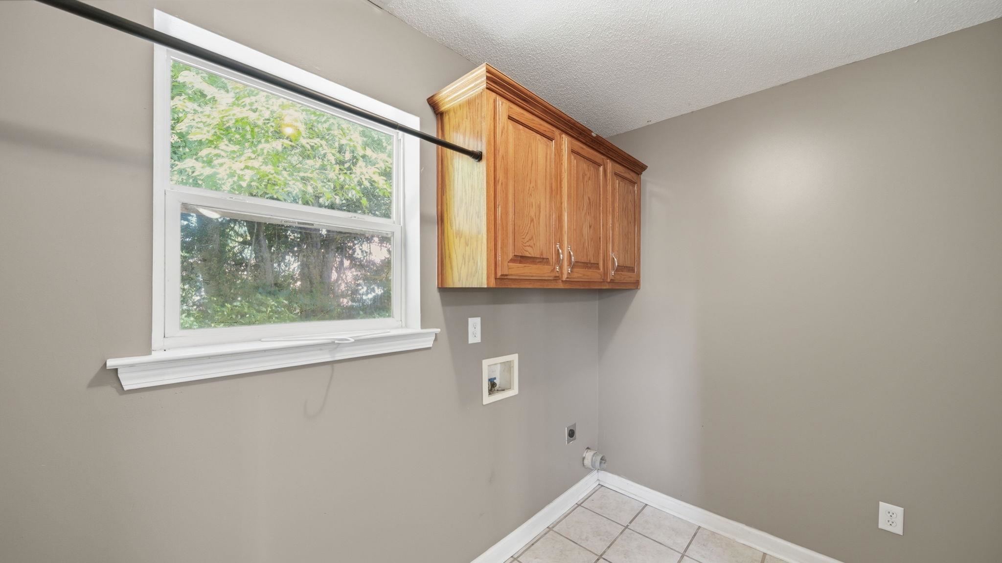 217 Rae Drive Munford, TN 38058 - Photo 23 of 40 Utility room featuring wood-finish cabinetry, tile flooring, and a window with white trim