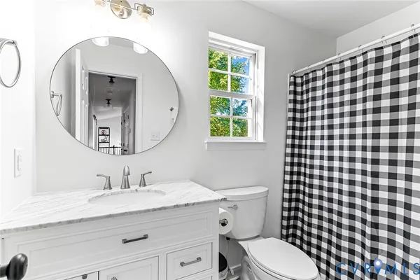 a bathroom with a granite countertop toilet a sink a mirror and a shower