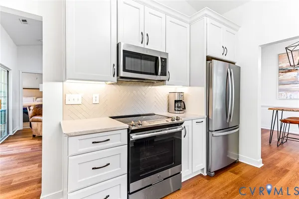a kitchen with stainless steel appliances white cabinets and wooden floor