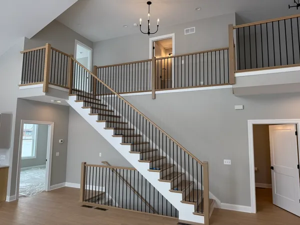 a view of staircase with railing and a chandelier