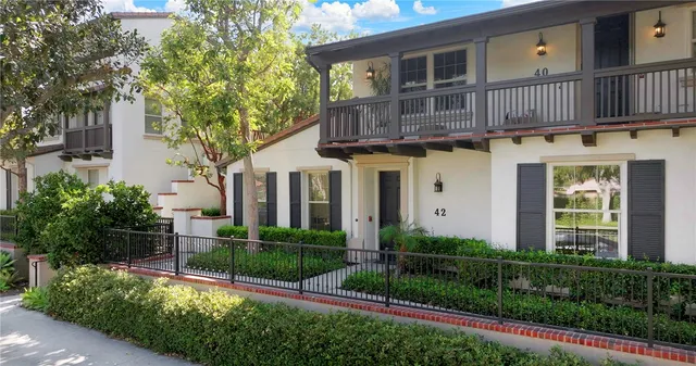a view of a house with brick walls and a yard with plants and a large tree