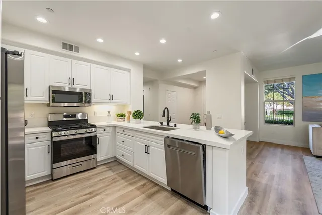a kitchen with stainless steel appliances granite countertop a stove top oven a sink dishwasher and a refrigerator
