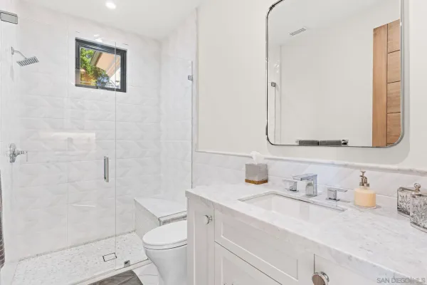 a utility room with stainless steel appliances white cabinets and a window