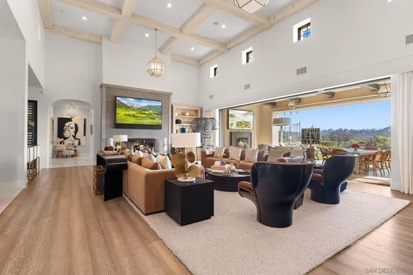 a living room with large couches kitchen view and a large window