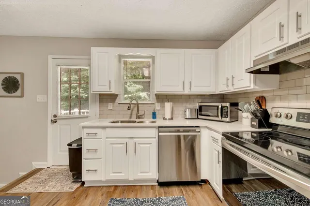 a kitchen with stainless steel appliances granite countertop a stove a sink and white cabinets