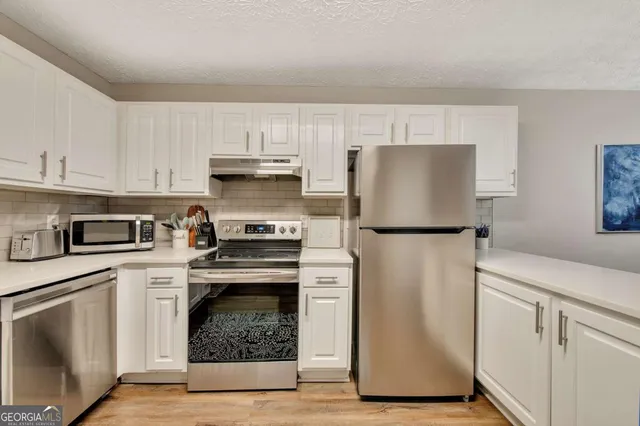 a kitchen with white cabinets and stainless steel appliances