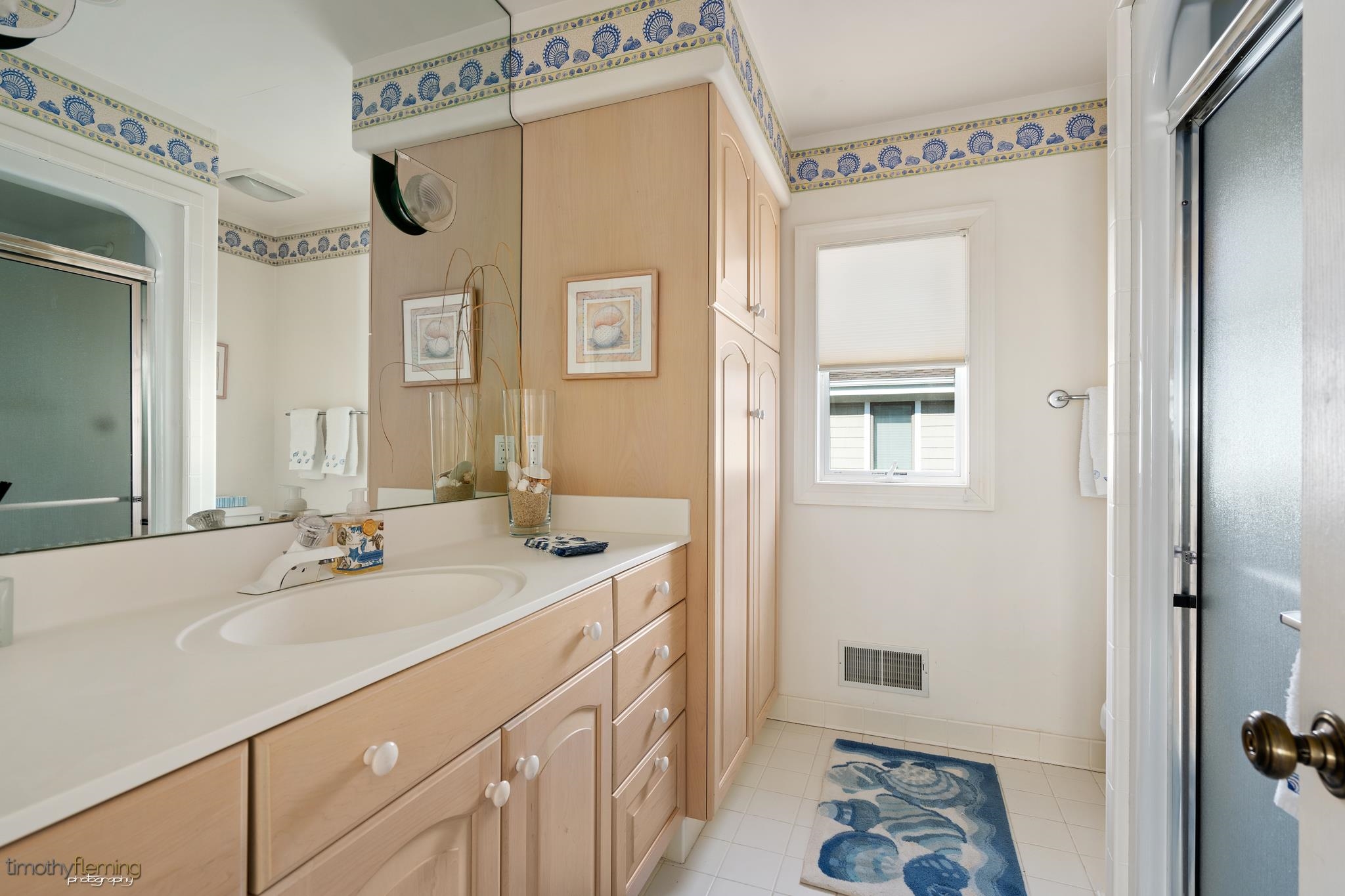 13 12th Street Avalon, NJ 08202 - Photo 13 of 24 a bathroom with a sink a mirror and a shower