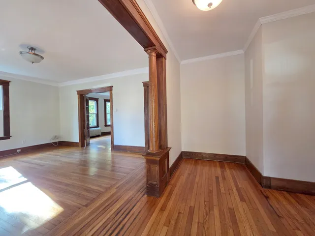 a view of empty room with wooden floor and fan