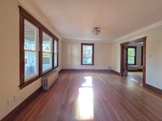 a view of an empty room with wooden floor and a window