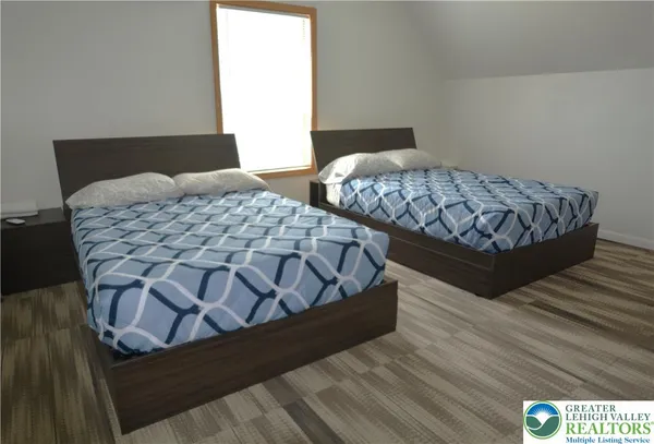 a bedroom with two beds with wooden floor