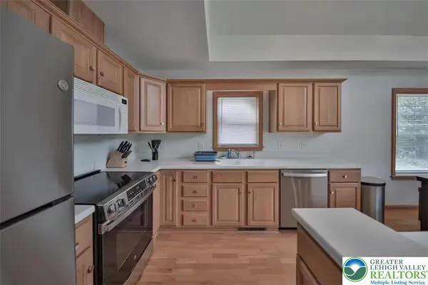 a kitchen with stainless steel appliances granite countertop a stove top oven a sink dishwasher and white cabinets with wooden floor