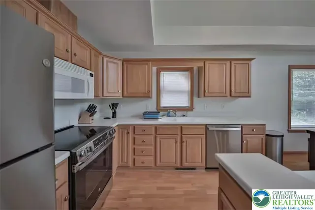 a kitchen with stainless steel appliances granite countertop a stove top oven a sink dishwasher and white cabinets with wooden floor