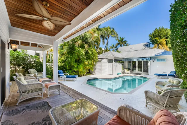 a view of a patio with couches table and chairs under an umbrella with a small yard