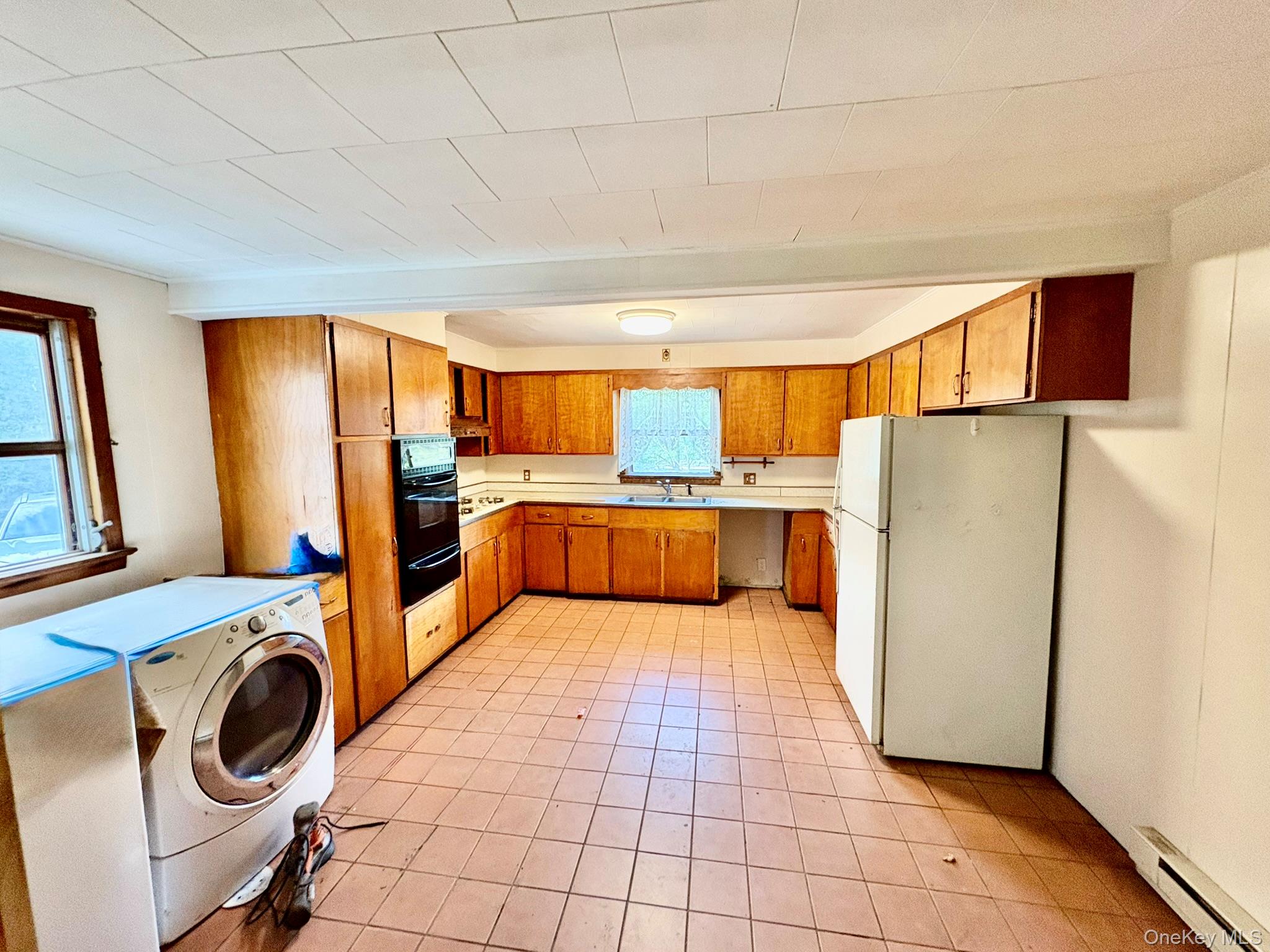 476 Old Rte 17 Livingston Manor, NY 12758 - Photo 5 of 39 Kitchen with freestanding refrigerator, brown cabinetry, a baseboard radiator, light countertops, and black oven