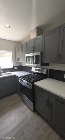 a kitchen with stainless steel appliances a sink cabinets and a wooden floor
