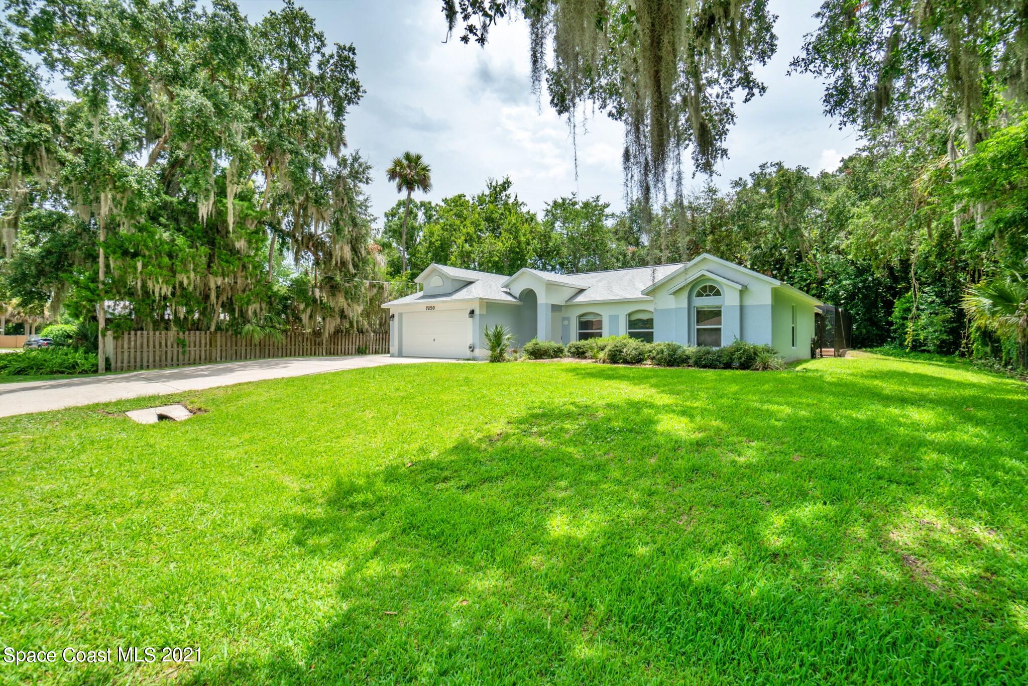 7250 Camilo Road Cocoa, FL 32927 - Photo 6 of 45 a white house with a big yard and large trees
