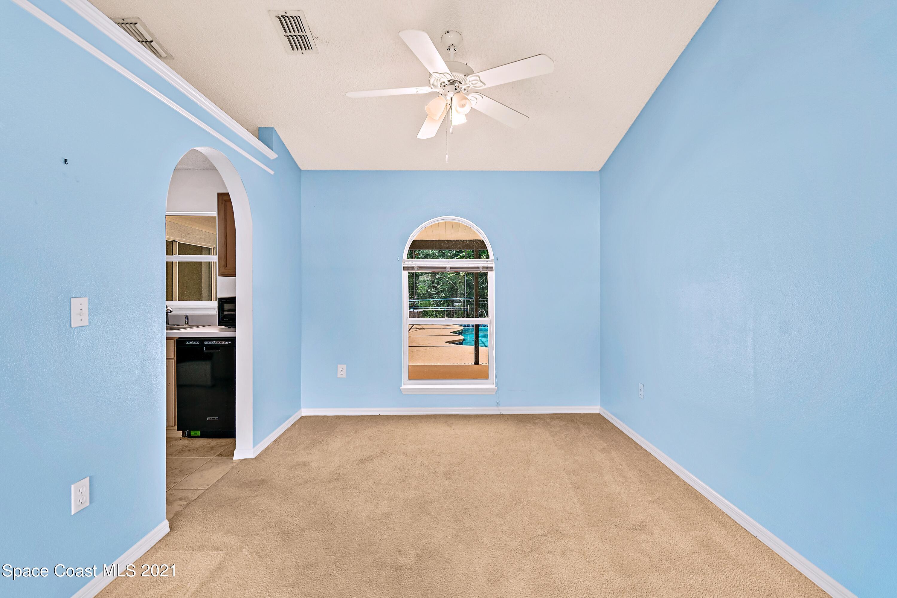 7250 Camilo Road Cocoa, FL 32927 - Photo 10 of 45 an empty room with windows and chandelier fan