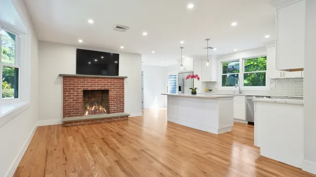 a open kitchen with white cabinets and a fireplace