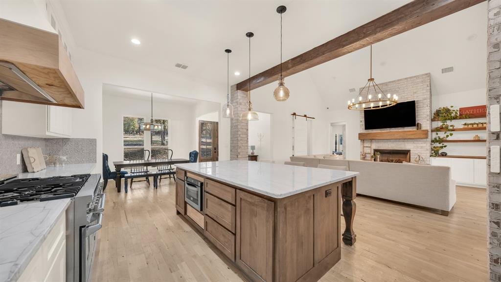 374 Glade Valley Road Azle, TX 76020 - Photo 7 of 38 a kitchen with a stove a refrigerator a kitchen island a sink and chairs with wooden floor
