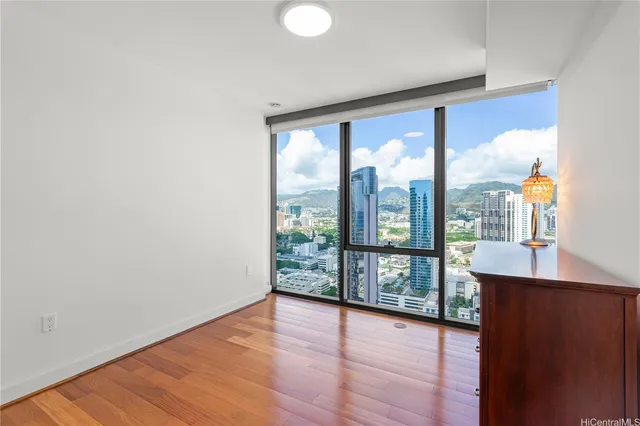 an empty room with wooden floor and windows with city view