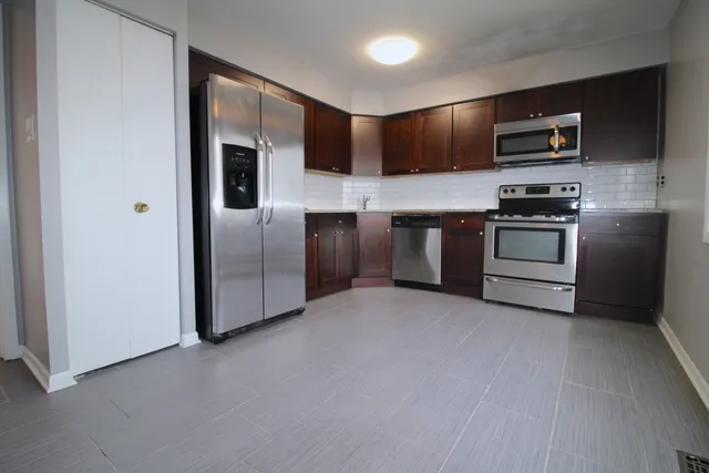 a kitchen with stainless steel appliances granite countertop a refrigerator and a stove top oven