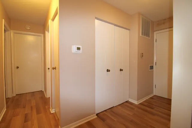 a view of an empty room with wooden floor and a bathroom