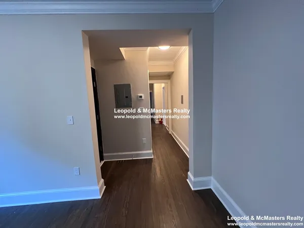 a view of a hallway with wooden floor and a cabinet