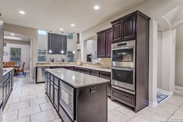 a kitchen with stainless steel appliances granite countertop a stove a sink and a refrigerator