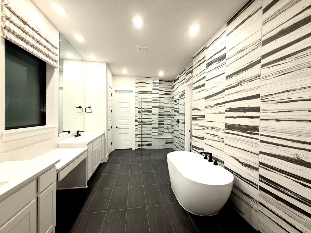 2002 Clearlight Lane Georgetown, TX 78633 - Photo 12 of 30 Bathroom featuring vanity, a freestanding bath, recessed lighting, a tile shower, and tile walls