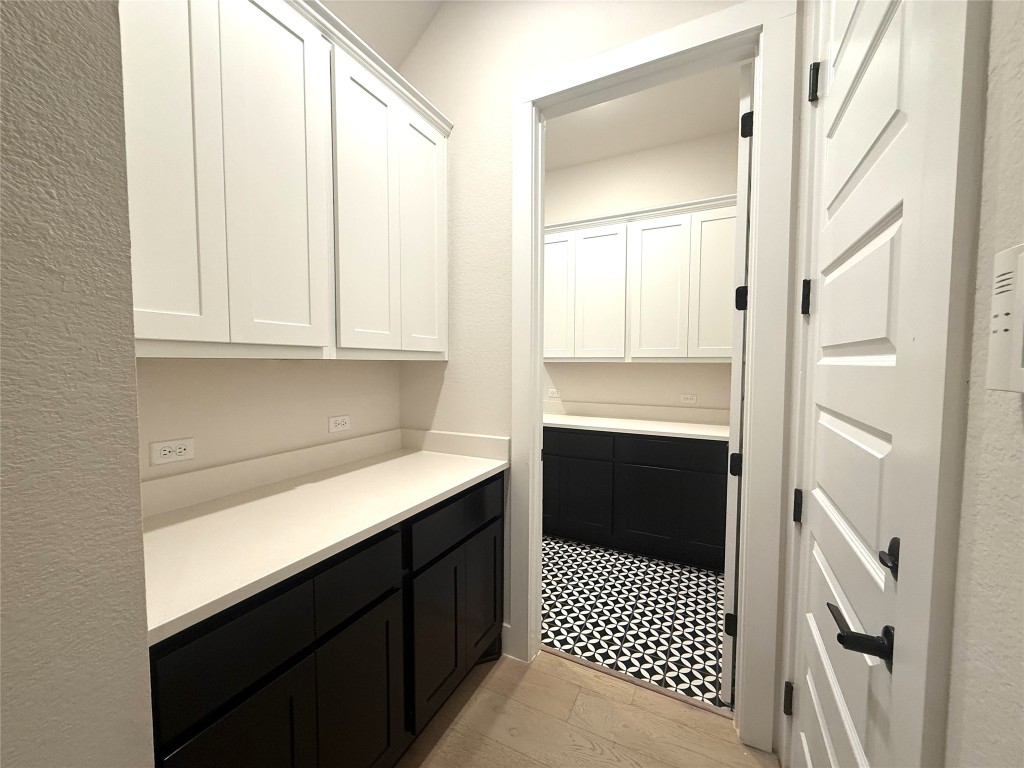 2002 Clearlight Lane Georgetown, TX 78633 - Photo 18 of 30 Bar with dark cabinets, white cabinetry, light countertops, and a textured wall