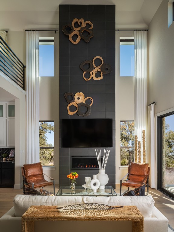 2002 Clearlight Lane Georgetown, TX 78633 - Photo 5 of 30 Living area featuring a towering ceiling, wood finished floors, a tiled fireplace, and plenty of natural light