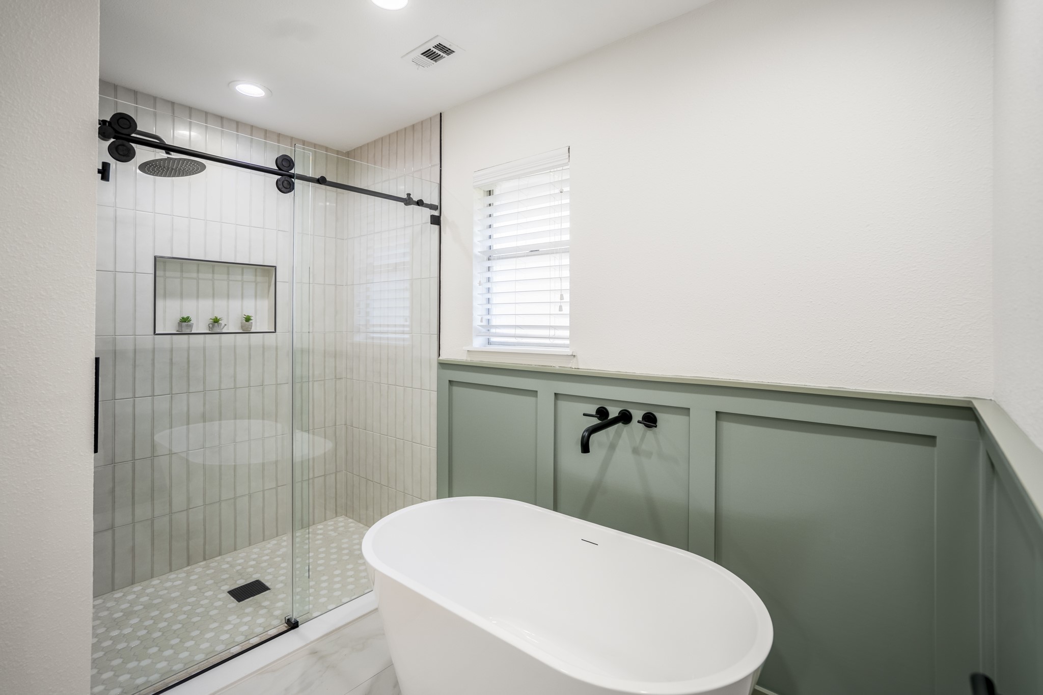 8006 Vickridge Lane Spring, TX 77379 - Photo 23 of 50 A closer look at the primary bath showcases the freestanding soaking tub and the beautifully updated shower with fresh tile and new glass. Thoughtful wall paneling and updated fixtures add an elevated touch to this calming retreat.