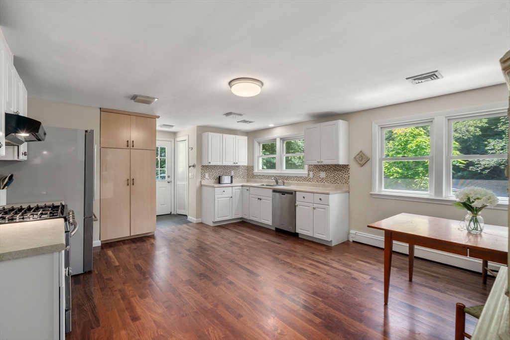 335 Conant Road Weston, MA 02493 - Photo 6 of 31 a kitchen with a refrigerator a sink dishwasher stove and white cabinets with wooden floor