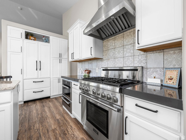 7 Sterling Loop Vineyard, UT 84059 - Photo 15 of 43 Kitchen featuring white shaker cabinetry, stainless steel range with matching range hood, dark countertops, patterned tile backsplash, and wood-finish flooring