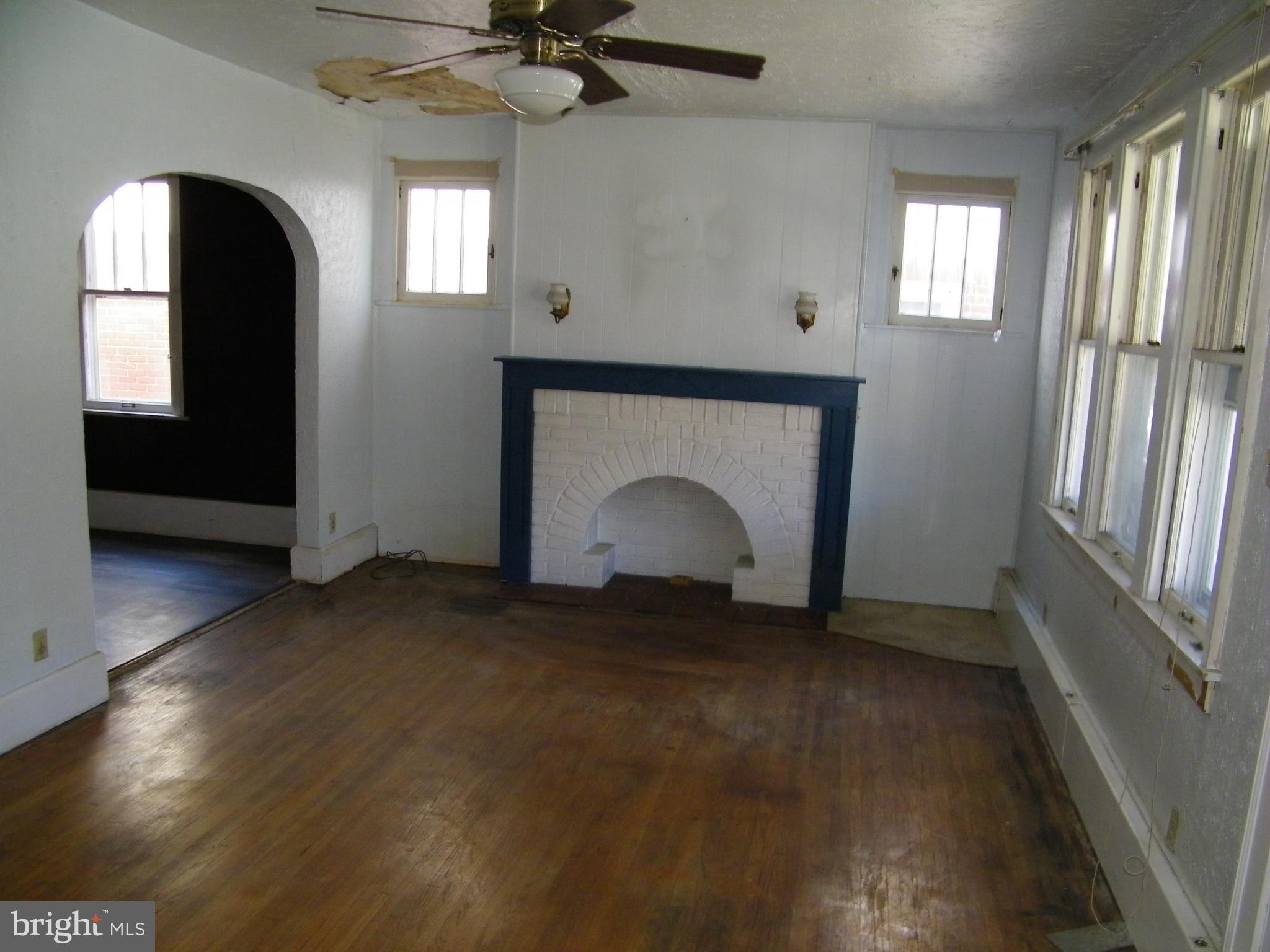 617 Frederick Street Cumberland, MD 21502 - Photo 6 of 16 an empty room with a fireplace and windows