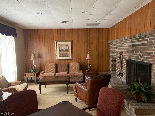2385 Covington Road, Unit 302 Akron, OH 44313 - Photo 16 of 19 Living room featuring a brick fireplace, wooden walls, a paneled ceiling, and light colored carpet