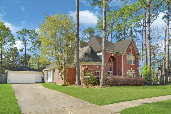 a view of a house with a big yard potted plants and a large tree