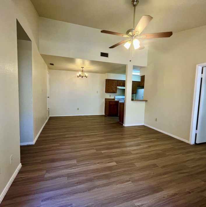 2114 Redwing Way Round Rock, TX 78664 - Photo 3 of 8 Unfurnished living room featuring dark wood-type flooring, a ceiling fan, suspended lighting, and a high ceiling
