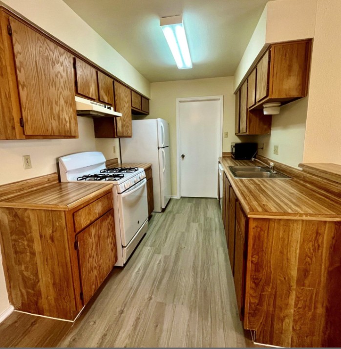 2114 Redwing Way Round Rock, TX 78664 - Photo 5 of 8 Kitchen featuring white appliances, light countertops, wood finish cabinets, and light wood-style flooring