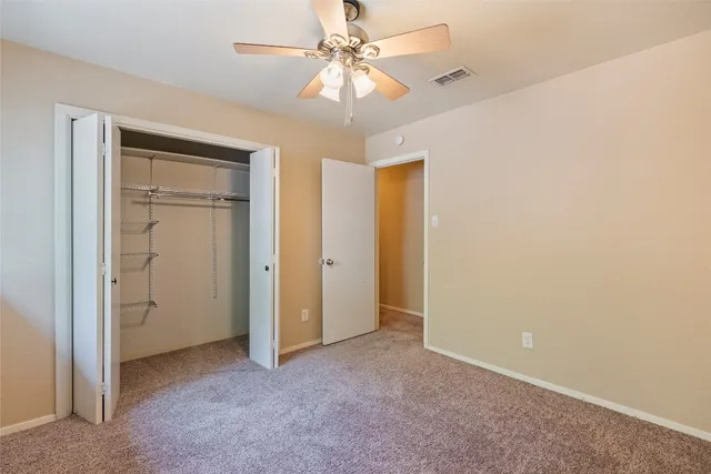 an empty room with closet and a chandelier fan