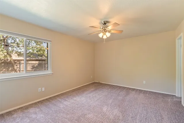 an empty room with a window and a fan