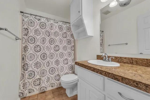 a bathroom with a granite countertop toilet sink and mirror