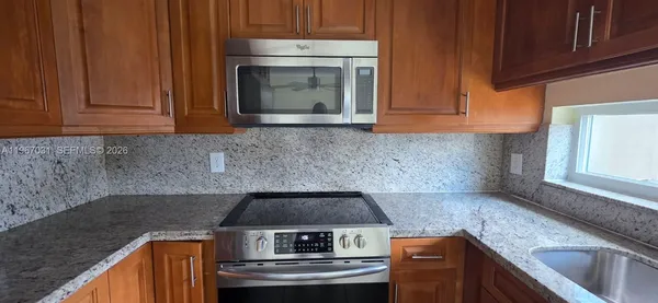 a kitchen with granite countertop wood cabinets and a stove top oven